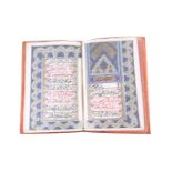 A leather bound booklet of Persian script, each page with stylised foliate decoration heightened