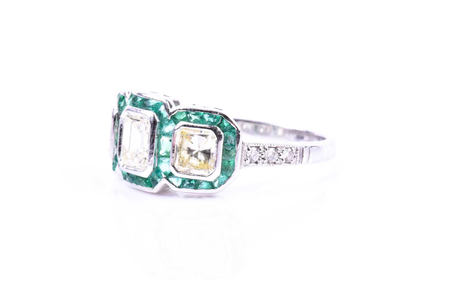 A diamond and emerald ring, set with an emerald-cut diamond flanked with two mixed square-cut - Image 2 of 5