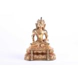 A Sino Tibetan gilt bronze figure of Manjushri, decorated with cast jewels and robes, seated on a