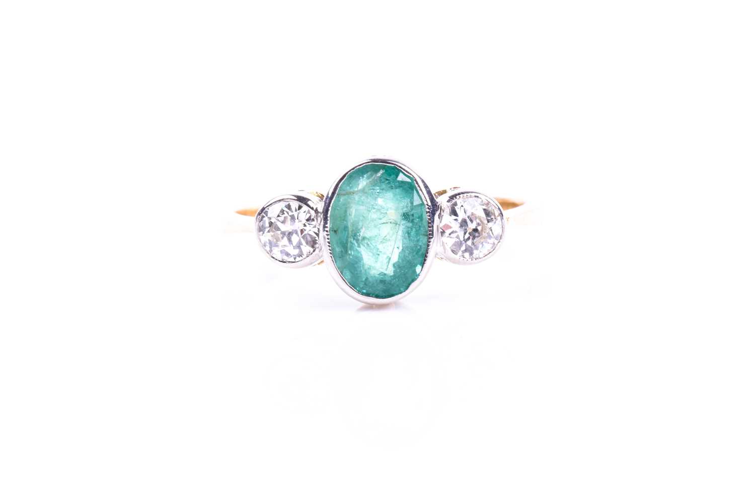 An 18ct yellow gold, diamond, and emerald ring, collet-set with a mixed oval-cut emerald of