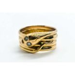 An unusual yellow metal snake ring, the curled snake with two small diamond accent eyes, engraved '