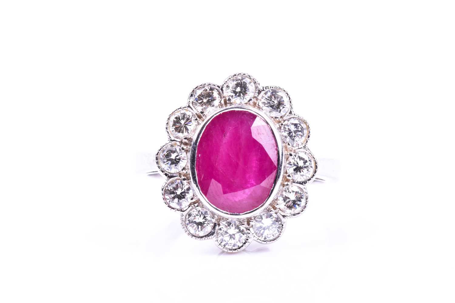 An 18ct white gold, diamond, and ruby cluster ring, set with a mixed oval-cut ruby of