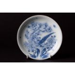 A Chinese blue and white saucer dish, painted with a pheasant perched on rockwork surrounded by