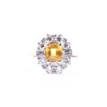 A diamond and yellow sapphire cluster ring, set with a mixed rectangular-cut yellow sapphire of