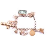 A 9ct yellow gold charm bracelet, suspended with various charms including a pram, a Paris charm, a