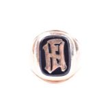 A yellow metal gents ring, bearing black onyx plaque with initials FH monogrammed to centre, shank