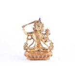 A Sino Tibetan style gilt bronze figure of Manjushri, the left hand in Gyan mudra, on a lotus