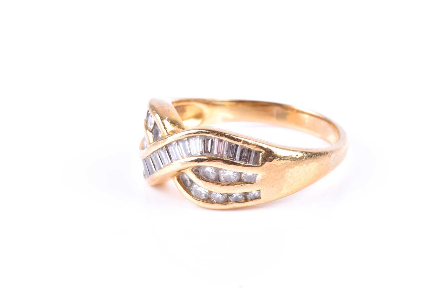 A yellow metal and diamond crossover ring, channel-set with mixed baguette-cut and round-cut - Image 3 of 4