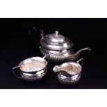A three piece white metal teaset, comprising teapot, creamer and sucrier, the tepaot marked 'Silver'