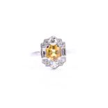 A platinum, diamond, and yellow sapphire ring, in the Art Deco style, set with a mixed-cut