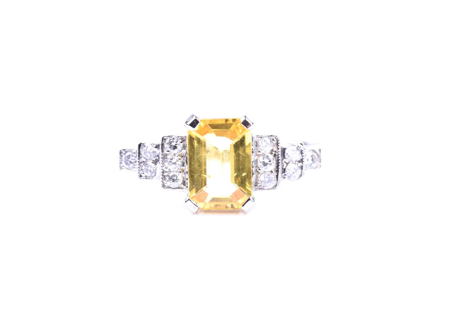 A platinum, diamond, and yellow sapphire ring set with a mixed emerald-cut yellow sapphire of