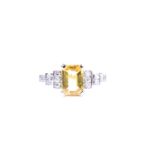 A platinum, diamond, and yellow sapphire ring set with a mixed emerald-cut yellow sapphire of