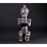 A Fang Byeri figure, Gabon, with long coiffure, carved holding a cup, with metal eyes, the arms with
