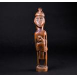 A Malaysian carved wood standing figure of a man, carved with a stern expression upon his face, a