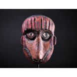 A carved and painted wood zoomorphic mask, Indonesia, painted predominantly in red and pink, with
