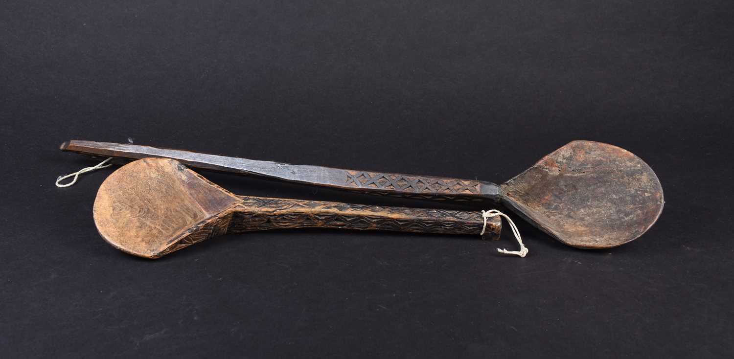 Two African carved wood spoons, each with geometric carved decoration, the smaller spoon carved to