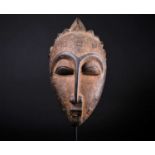 A Punu mask, Gabon, with short linear coiffure within short knots, the forehead and face with groups