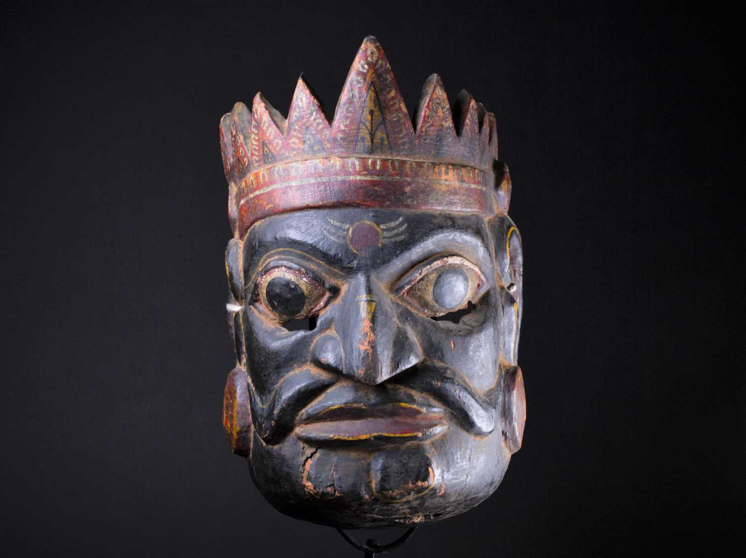 An Indonesian carved and painted ceremonial male mask, in yellow, red, white and black pigment,