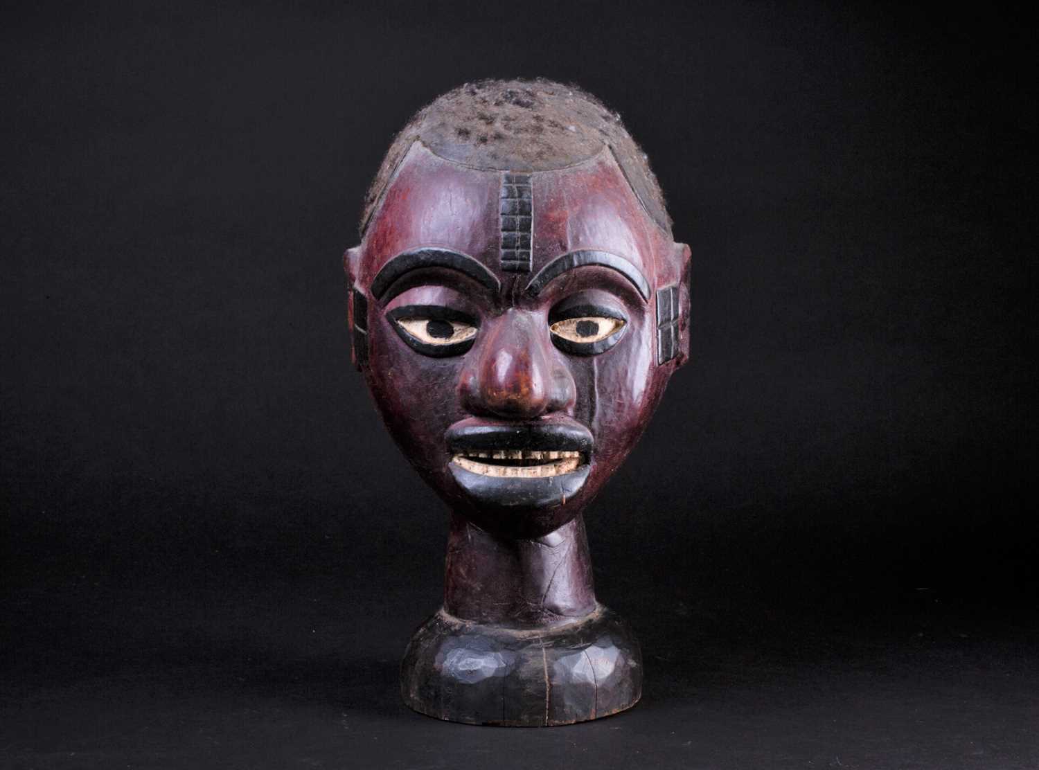 An Ejagham (Ekoi) leather bound carved wood headpiece, the head with applied hair, the maroon