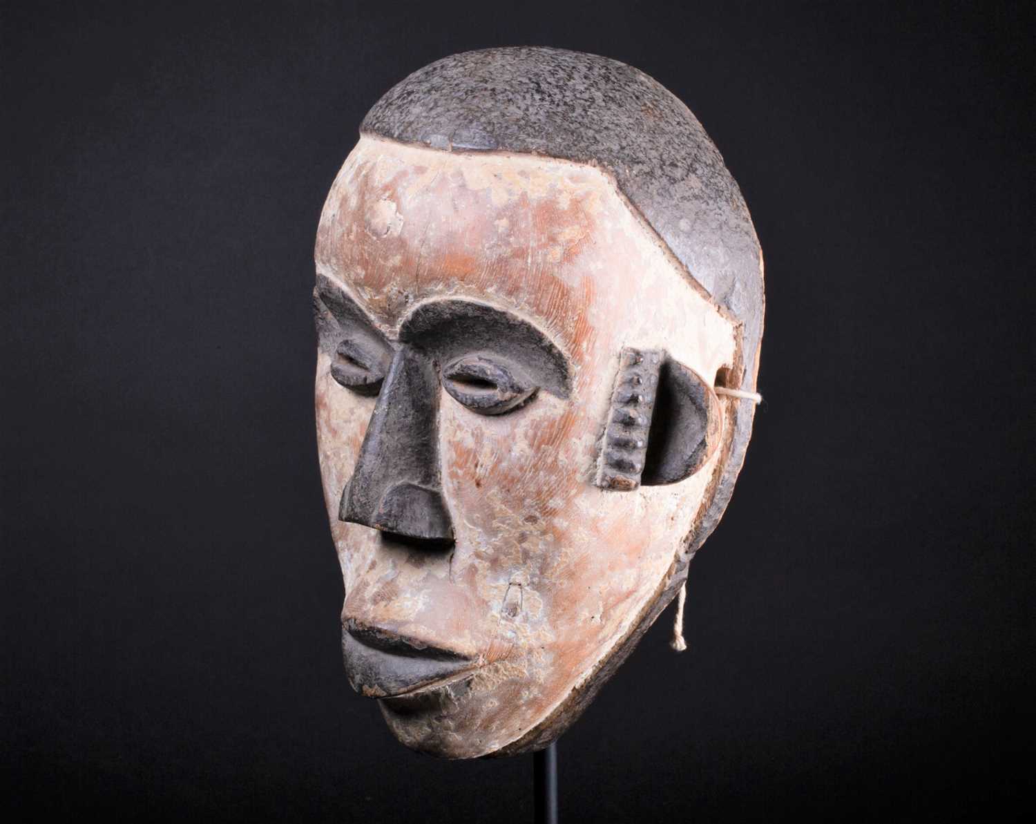 An Igbo mask, Nigeria, with short coiffure, highlighted in black against a white pigment ground,