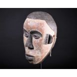 An Igbo mask, Nigeria, with short coiffure, highlighted in black against a white pigment ground,