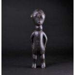 An East African carved wood standing figure of a man, Possibly Kamba, Kenya, his hands resting