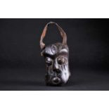 An African carved wood miniature mask/bell, the distorted face with coffee bean eyes and incised