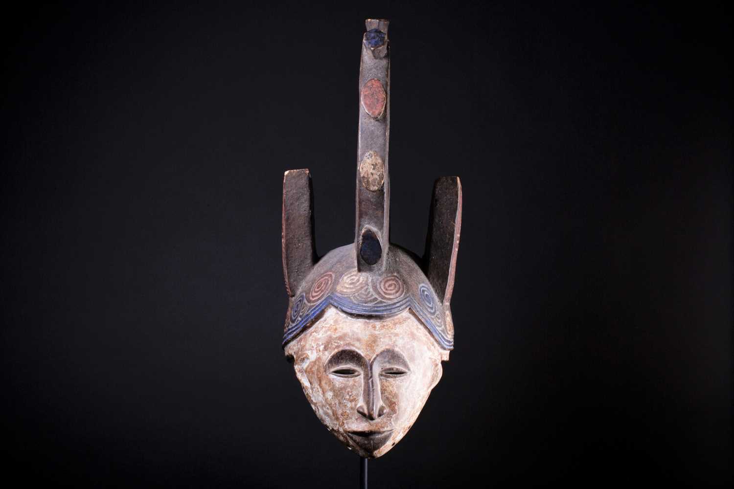 An Igbo Maiden Spirit mask, Nigeria, in red, blue and white pigment, the edges pierced with holes, - Image 2 of 6