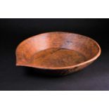 An Indian carved wood bowl, the rim terminating in a point, the exterior with adzed sloping sides, a