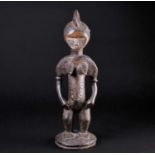 A Senufo female standing figure, Ivory Coast, with crested coiffure, pointed breasts, the body