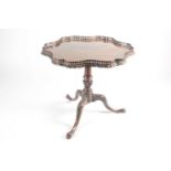 A late George III, mahogany flip-top tripod silver table with a shaped outline and a pierced