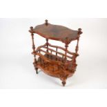 A Victorian figured walnut cartouch-topped three-tier table / Canterbury, with carved finials and