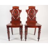 A pair of early Victorian solid mahogany cartouch-backed hall chairs, with shaped seats and raised