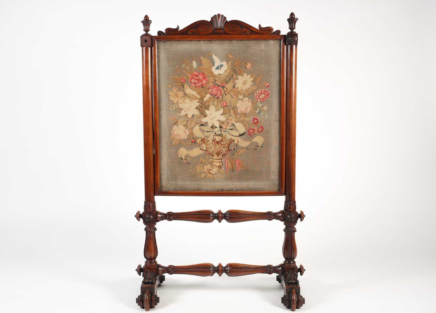 A Victorian mahogany and petit point firescreen, with shell and scroll decoration over turned