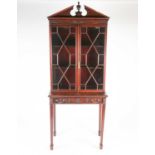 A Geo III style carved mahogany console bookcase, with 'broken arch and urn' pediment over a pair of