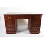 An early 20th century walnut, kneehole, pedestal desk with inset leather writing surface and
