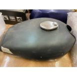 A group of three fuel tanks including a Yamaha RD125/200 red tank, a 1957 Triumph green tank, and