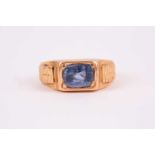 A yellow metal and sapphire ring, set east to west with a mixed rectangular-cut sapphire, the