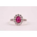 A ruby and diamond cluster ring, the oval mixed-cut ruby, approximately 1ct, surrounded by twelve