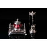 A Victorian silver plated inkwell with a square base and cranberry glass reservoir with bow pen