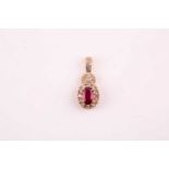 A 14k yellow gold, diamond, and ruby pendant, set with a mixed oval-cut ruby within a border of