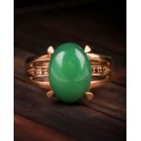 A jade and diamond ring, the oval jade cabochon, 14 x 10 mm, four claw mounts, to open-work