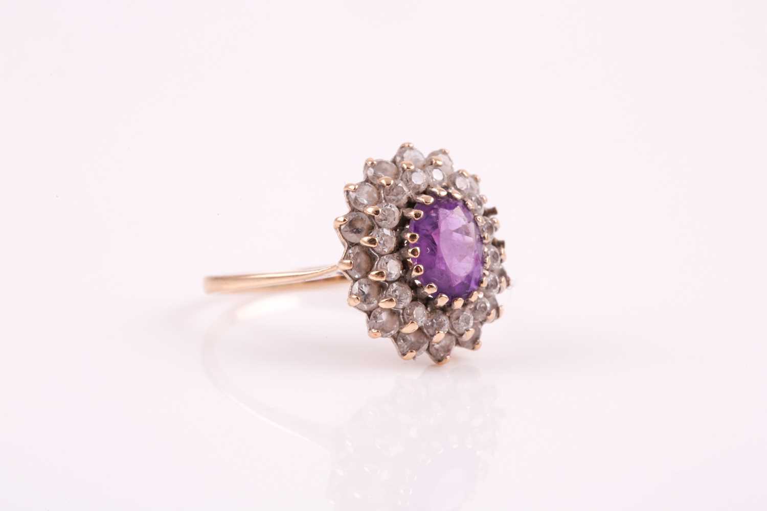 A 9ct yellow gold, amethyst, and white paste stone cluster ring, set with a mixed oval-cut - Image 5 of 6