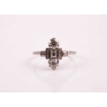 An Art Deco diamond ring; set with two round brilliant cut diamonds above and below a step cut,