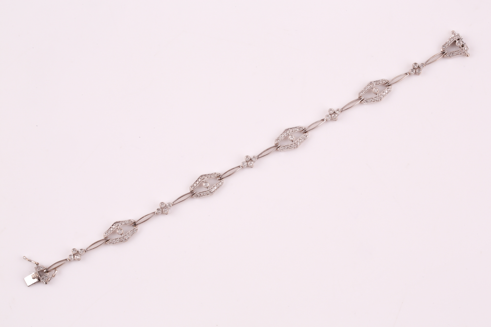 A diamond bracelet; of alternating diamond set openwork lozenge and four stone diamond clusters - Image 8 of 14