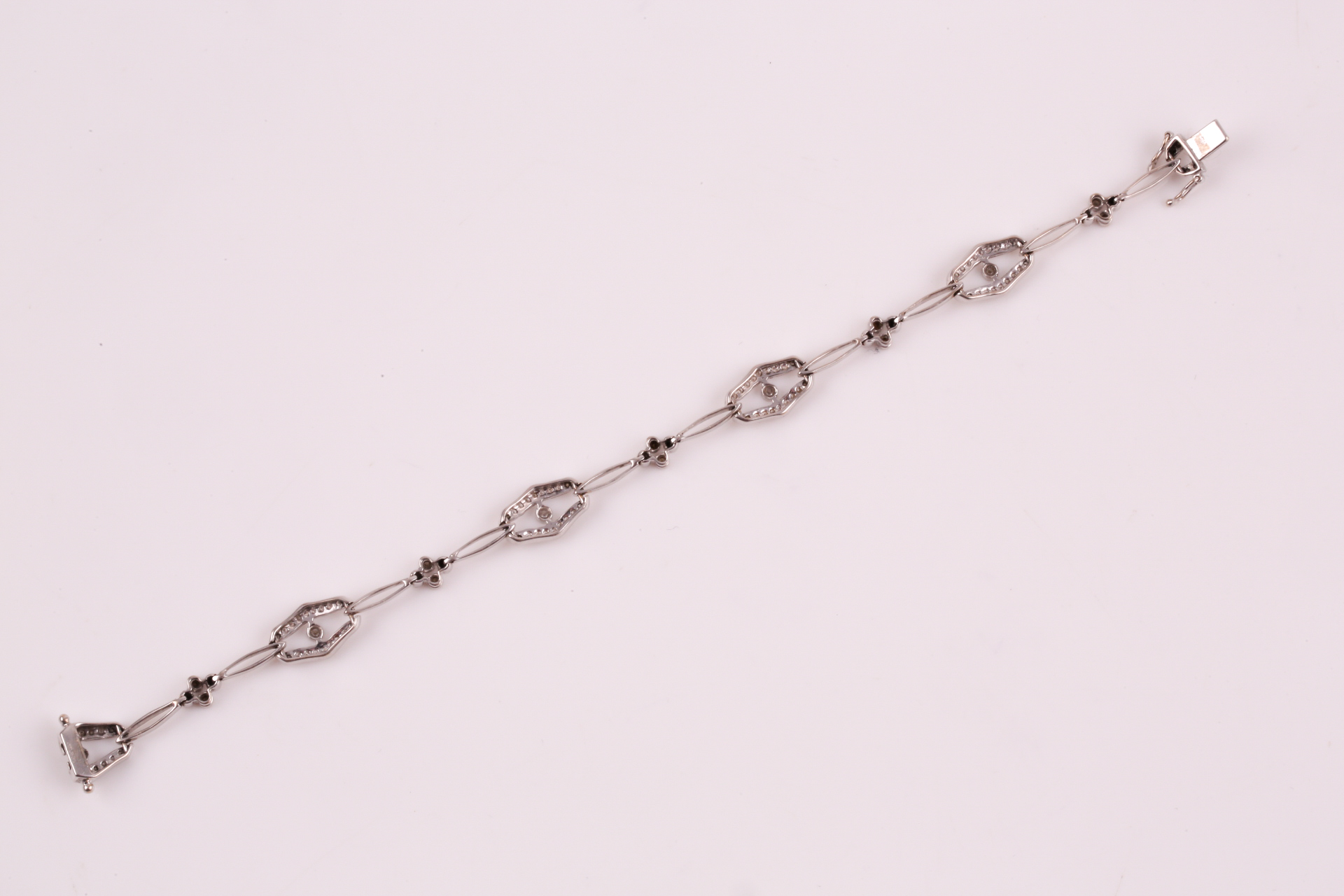 A diamond bracelet; of alternating diamond set openwork lozenge and four stone diamond clusters - Image 13 of 14