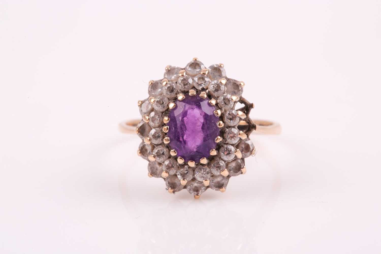 A 9ct yellow gold, amethyst, and white paste stone cluster ring, set with a mixed oval-cut