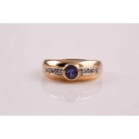 A tanzanite and diamond ring, the circular cut tanzanite in rub-over mount between three stone