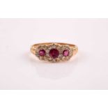 An 18ct yellow gold, diamond, and ruby ring, set with three round-cut rubies within a border of