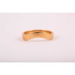 An 18ct yellow gold band ring, with shaped design (to fit around another ring or to be worn